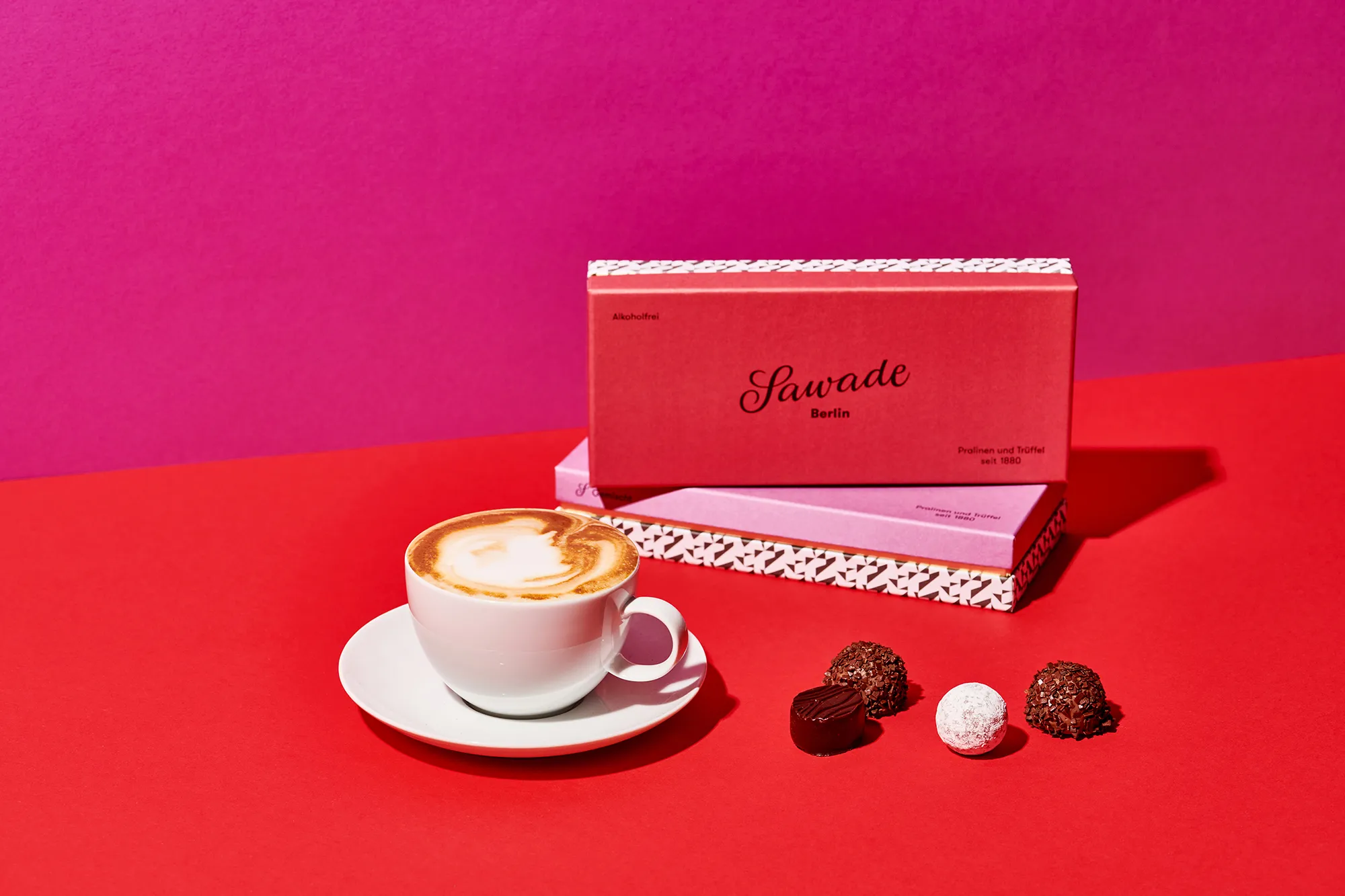 Stimmungsbild: Pralinenschachteln mit einer Tasse Kaffee und einzelnen Pralinen daneben